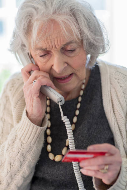 senior kvinna ger kreditkortsuppgifter på telefonen - bedrägeri telefon bildbanksfoton och bilder