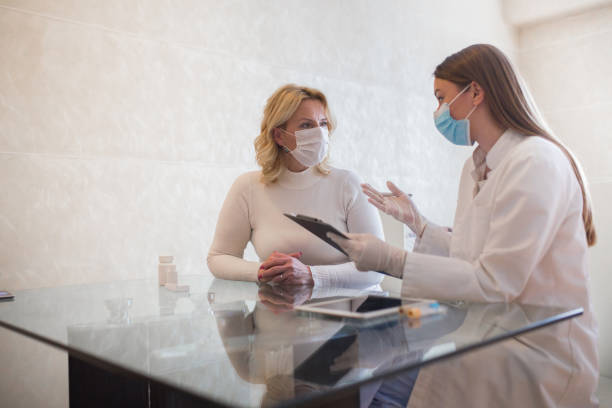 Senior woman having conversation with health care giver at her home stock photo