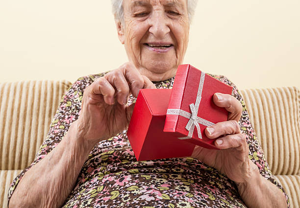 старший женщина держит подарочную коробку, - happy new year стоковые фото и изображения