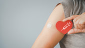 istock senior woman holding red heart shape with  syringe and showing her arm with bandage after got vaccinated or inoculation due to spread of corona virus, population, social or herd immunity concept 1328664977