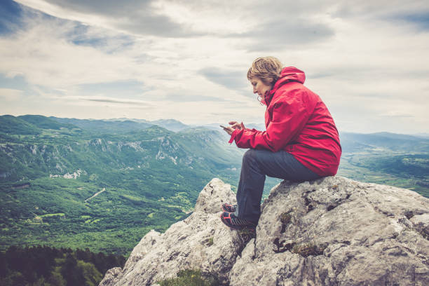 Senior woman in the mountains using her smart phone stock photo