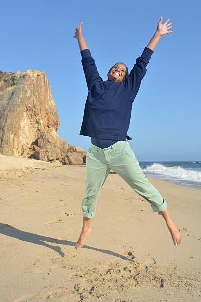 Senior Woman Jumping for Joy on Beach stock photo