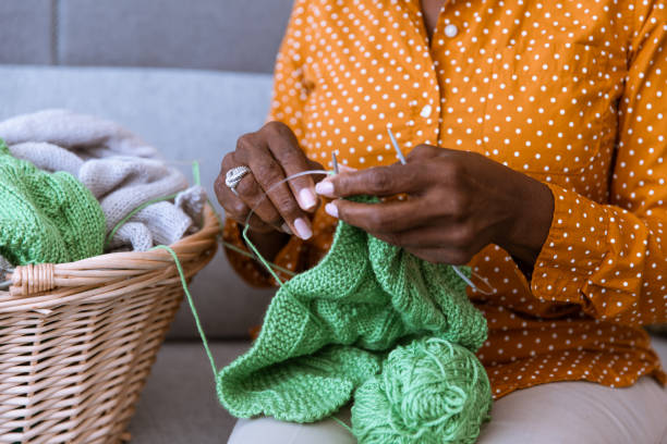African American senior sitting on the couch and knitting at home