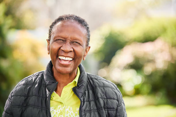 Senior woman laughing while standing in a park stock photo