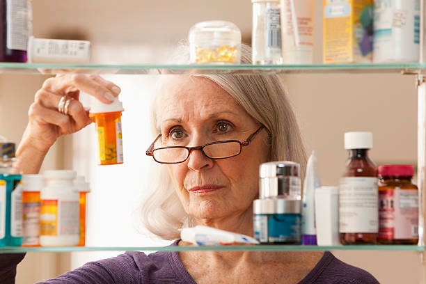 Woman looking for medicine inside a glass cabinet.