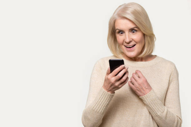 senior kvinna tittar på smartphone skärmen känns häpnad studio shot - sms imposter elderly bildbanksfoton och bilder