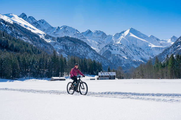senior woman on mountain bike in winter nice senior woman riding her electric mountainbike on a sunny winter day in the Allgau alps near Oberstdorf, Bavaria, Germany allgau alps stock pictures, royalty-free photos & images