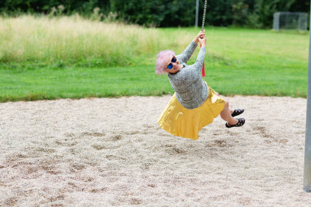 Senior woman on swing at playground stock photo