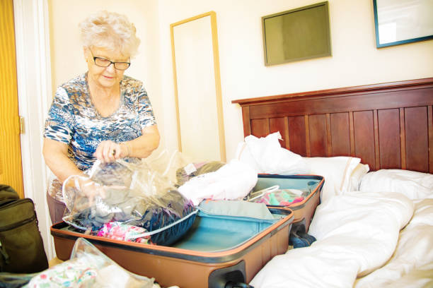 Senior woman placing clothes in a luggage using plastic bags Senior woman placing clothes in a luggage using plastic bags to prevent bed bug infestation. infestation bed bug stock pictures, royalty-free photos & images