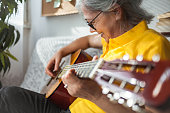 istock Senior woman playing guitar ay home 1289054436