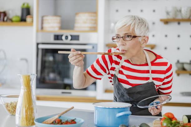 Senior woman preparing food at home stock photo