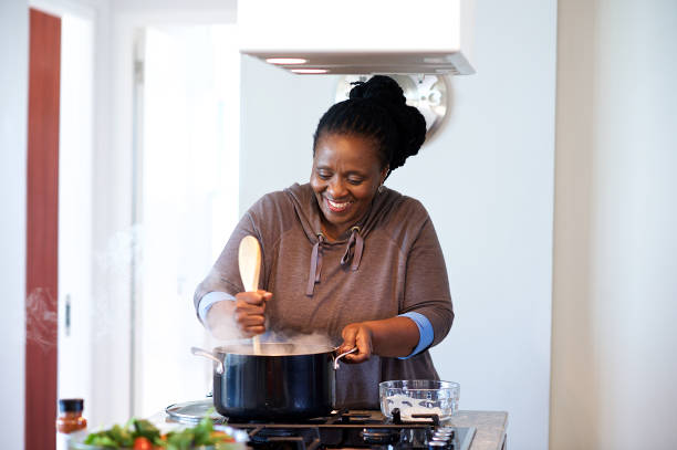 Senior woman preparing traditional pap on a gas stove looking down stock photo