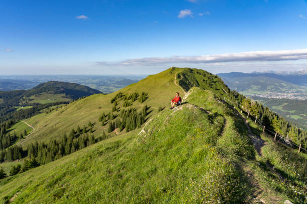 senior woman resting during a hike in the Allgau Alps pretty senior woman resting during a hike in the early evening in warm dawn light on the ridge of the Nagelfluh chain in the Allgau Alps near Immenstadt, Bavaria, Germany allgau alps stock pictures, royalty-free photos & images