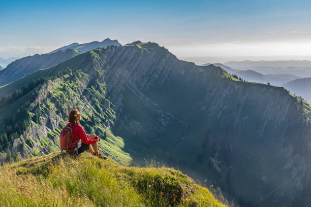 senior woman resting during a hike in the Allgau Alps pretty senior woman resting during a hike in the early evening in warm dawn light on the ridge of the Nagelfluh chain in the Allgau Alps near Immenstadt, Bavaria, Germany allgau alps stock pictures, royalty-free photos & images