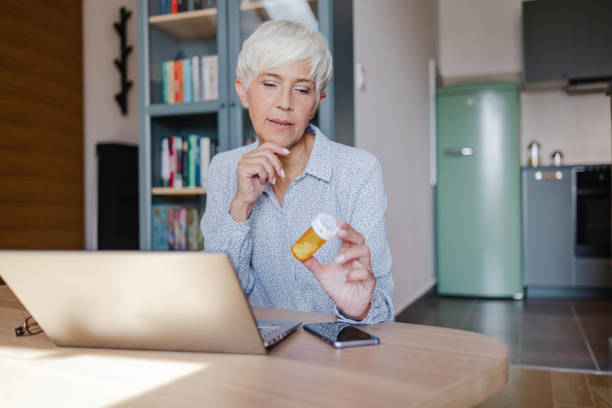 Senior woman searches for information about pills on the internet stock photo