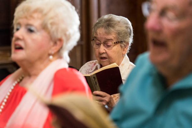 Senior woman sings from her hymn book in church Senior woman sings from her hymn book in church chapel stock pictures, royalty-free photos & images