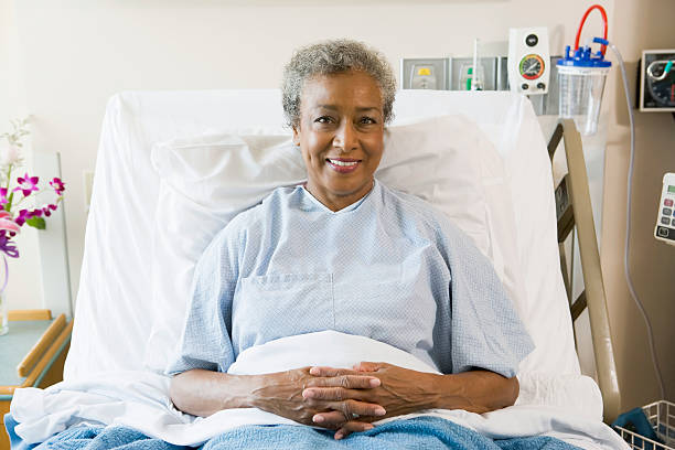 Senior Woman Sitting In Hospital Bed Senior Woman Sitting In Hospital Bed smiling patient in hospital bed stock pictures, royalty-free photos & images