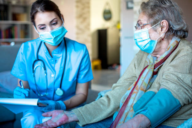 Senior woman sitting while district nurse is measuring her blood pressure. stock photo