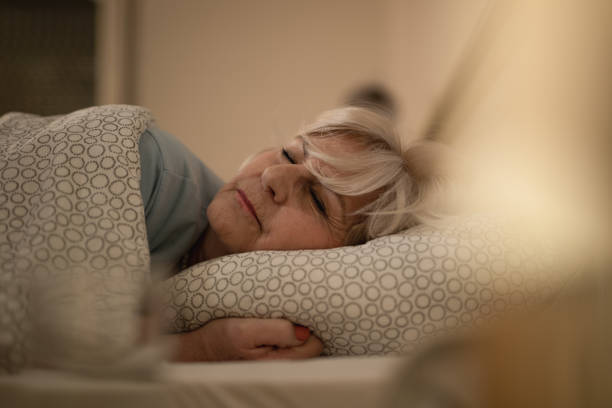 äldre kvinna sover på sängen på natten. - nap middle age woman bildbanksfoton och bilder