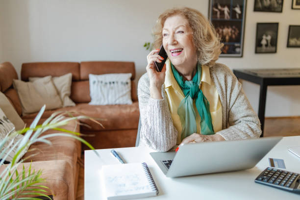 Senior woman talking on the phone at home stock photo