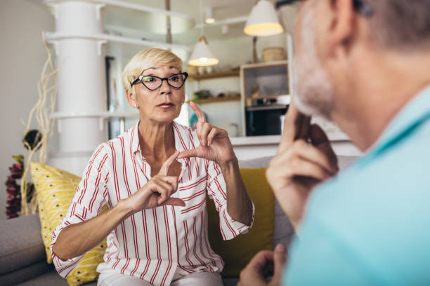 Senior woman talking using sign language with her husband at home. stock photo