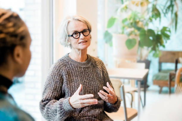 Senior woman talking with participants in a group therapy session stock photo