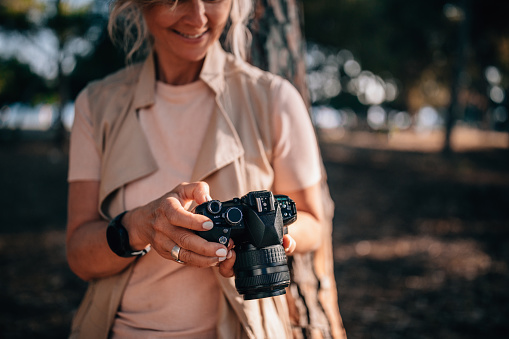 Senior woman using camera and looking at photos in nature