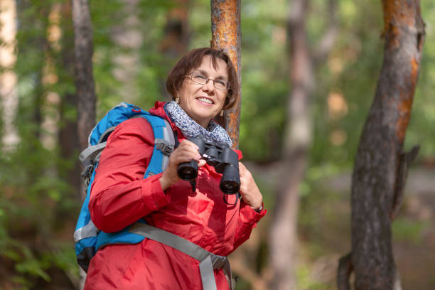senior kvinna med kikare i en skog - fågelskådning bildbanksfoton och bilder