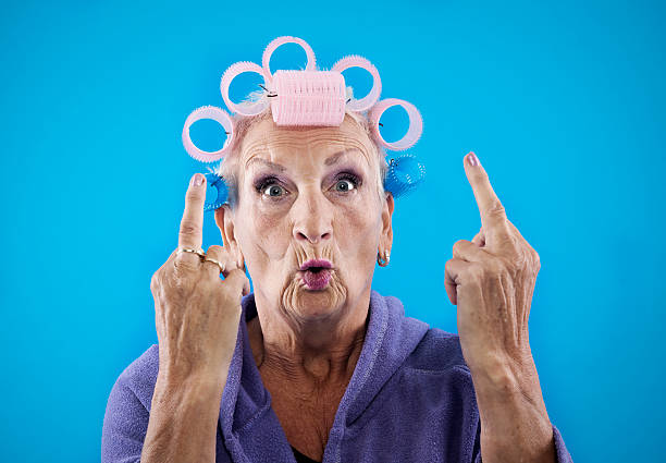Senior woman with obcene gesture enior woman, 68 years old, with curlers in her hair. ugly old women stock pictures, royalty-free photos & images