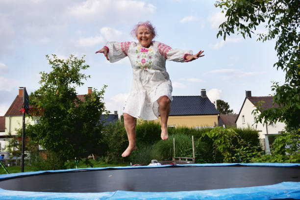 Senior woman with overweight jumping on trampoline stock photo