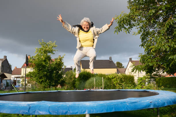 Senior woman with overweight jumping on trampoline stock photo