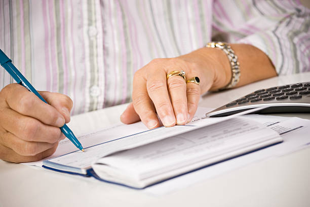 Senior woman writing in her checkbook stock photo