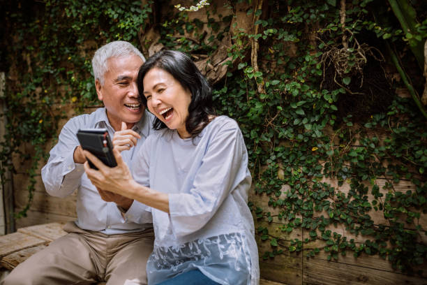 Seniors Having Video Call On Phone With Their Family Happy Senior Couple Having Video Call Using Their Phone baby boomers stock pictures, royalty-free photos & images