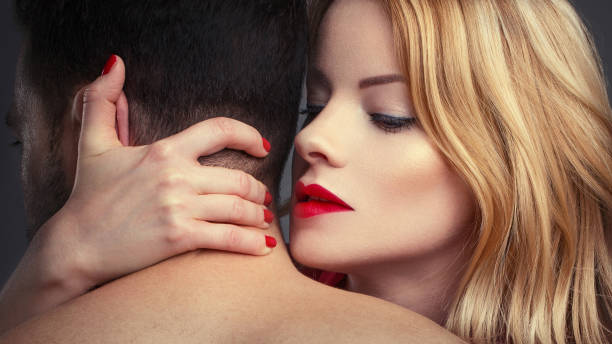 Sensual blonde woman holding man in arms at night stock photo