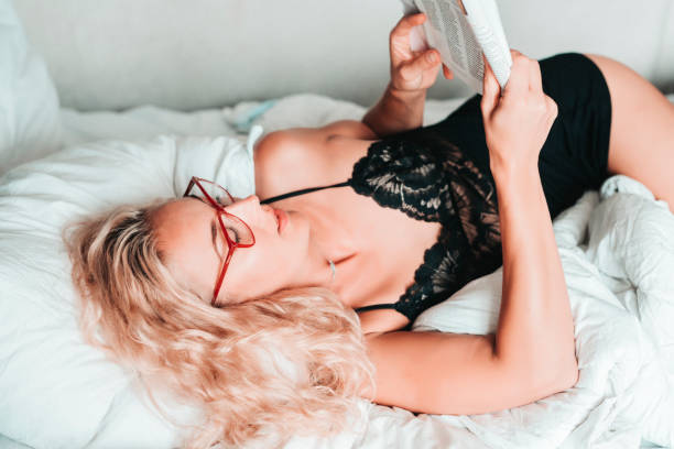 Sensual female reading in a bed stock photo