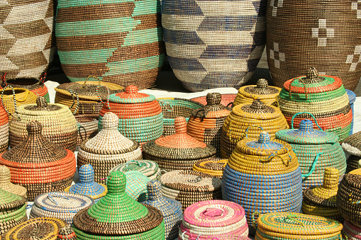 These colorful woven African seagrass storage baskets are handmade by women in Senegal, Congo, and Angola. The baskets are made from natural dried sea grass and are colored using natural dyes. The designs are ethnic in origin. The baskets seen here are on display in a street market.