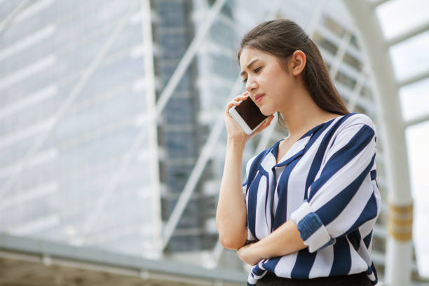Serious asian young business woman talking on mobile phone in urban city . outdoor. stock photo