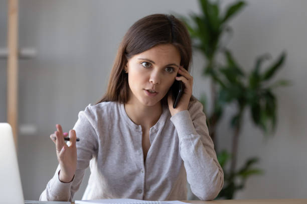 Serious focused manager consulting client talking on the phone Serious focused manager consulting client talking on the phone making business call at work, young female worker or customer speaking by mobile complaining on service or explaining solving problem complaining stock pictures, royalty-free photos & images