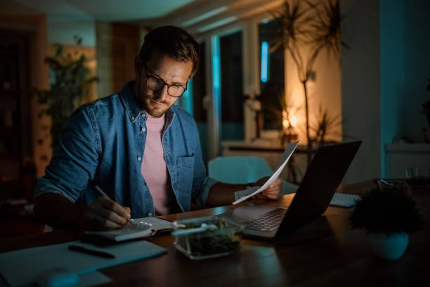 Serious handsome man working late from his home office stock photo