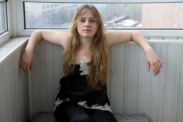 serious teen girl sitting on balcony stock photo