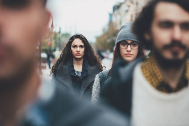 Serious woman in the crowd Portrait of a serious young woman among other defocused faces on the street blank expression photos stock pictures, royalty-free photos & images