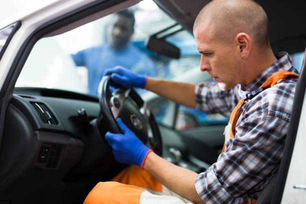 Service engineer in uniform repairs a car steering wheel stock photo