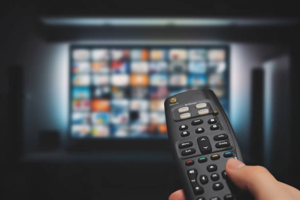 VOD service on television. TV streaming concept VOD service on television. Man watching TV, streaming service, video on demand, remote control in hand. remote control stock pictures, royalty-free photos & images