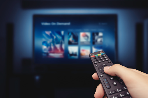 Vod Service Screen With Remote Control In Hand Stock Photo - Download Image Now - iStock