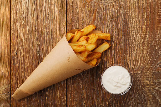 Serving Belgian fries served in a paper box. Serving Belgian fries served in a paper tube, with or without a dip. On a wooden table. belgian culture stock pictures, royalty-free photos & images