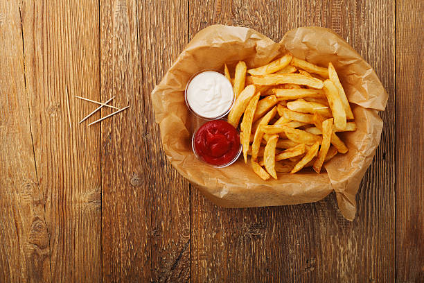 Serving Belgian fries served on paper in the basket. Serving Belgian fries served on paper in the basket, with one or two dips. On a wooden table. belgian culture stock pictures, royalty-free photos & images