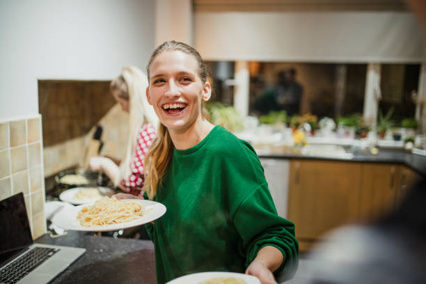 Serving Food at a Home Dinner Party Young woman is serving spaghetti carbonara at her home dinner party. roommate stock pictures, royalty-free photos & images