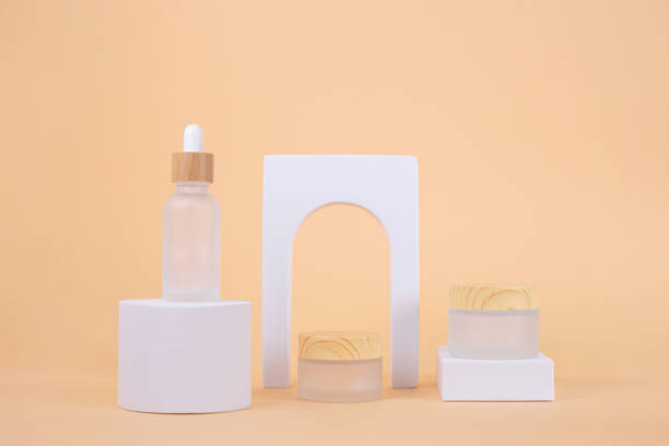 Set of Cosmetic products bottles on white podium with arch on beige background. stock photo