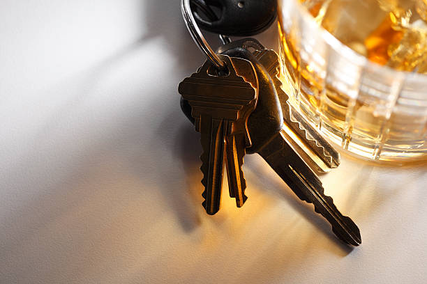 Set of keys sitting at base of glass of alcohol stock photo