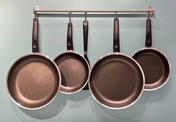 Set of kitchen metallic pans hanging on a pot rack in the kitchen stock photo